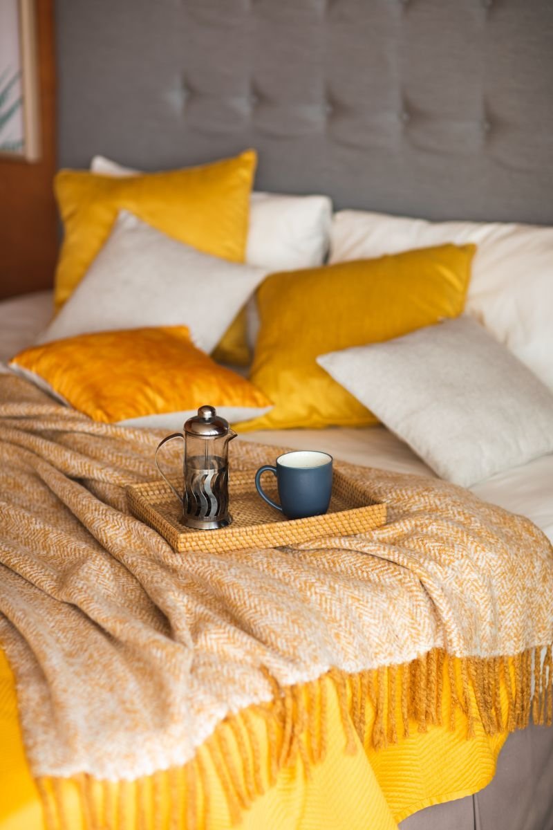 Schlafbereich mit Bett, gelben Kissen und Tablett